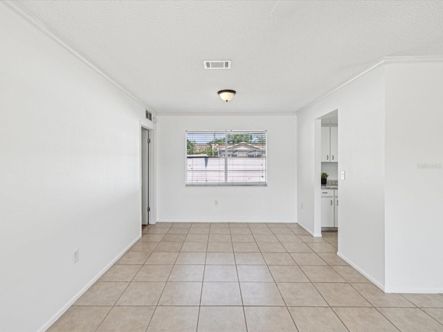 spare room with crown molding, a textured ceiling, and visible vents