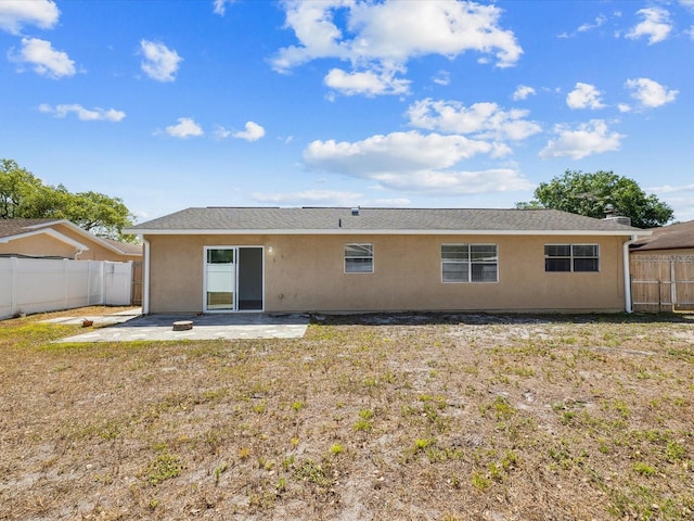 rear view of property featuring a yard, a fenced backyard, a patio area, and stucco siding