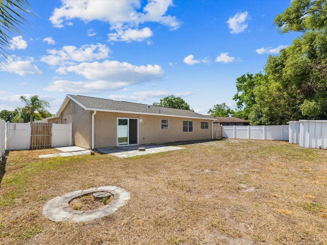 back of property featuring a lawn, a gate, a fenced backyard, a patio, and stucco siding