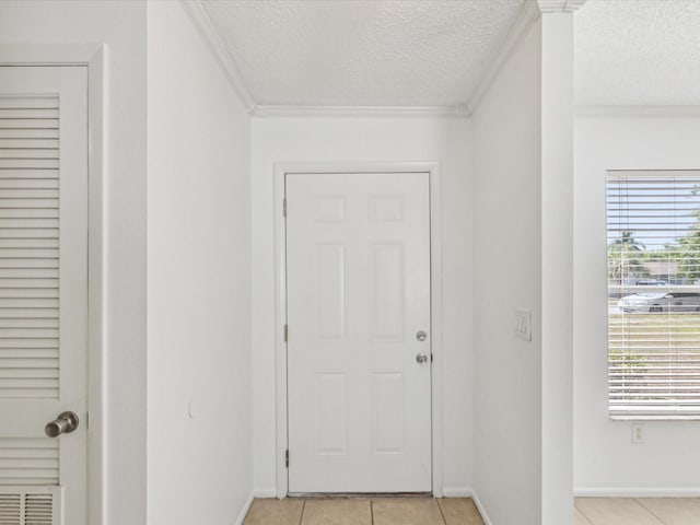 entryway with light tile patterned floors, baseboards, ornamental molding, and a textured ceiling