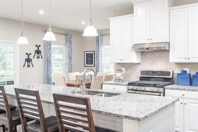 kitchen featuring a sink, gas stove, a kitchen island with sink, tasteful backsplash, and under cabinet range hood