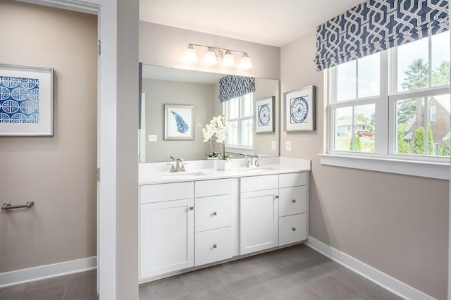 bathroom with a sink, baseboards, tile patterned floors, and double vanity
