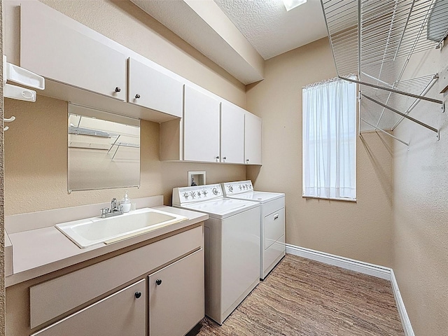 3464 Misty View Dr, Spring Hill, FL 34609 - washroom with baseboards, cabinet space, washing machine and clothes dryer, light wood-style flooring, and a textured wall