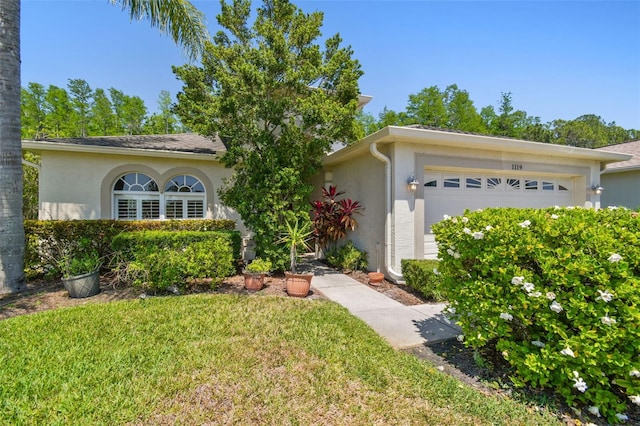 view of front of house featuring stucco siding, a front lawn, and a garage