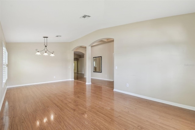 unfurnished room with arched walkways, baseboards, light wood-style flooring, and visible vents