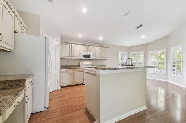 kitchen featuring white appliances, visible vents, an island with sink, and light wood-type flooring