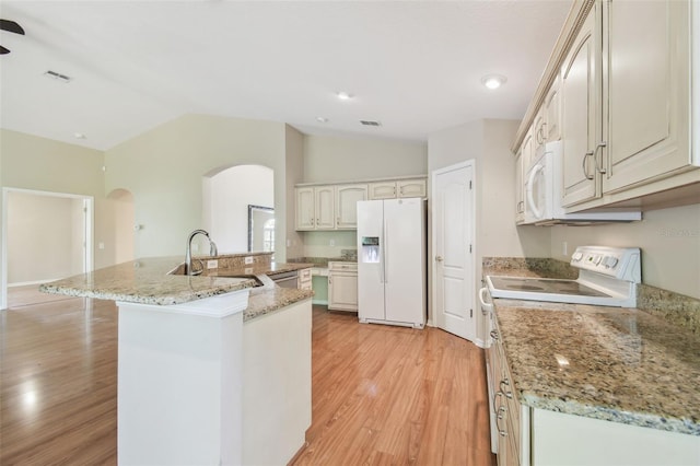 kitchen with arched walkways, light wood-style flooring, vaulted ceiling, and white appliances