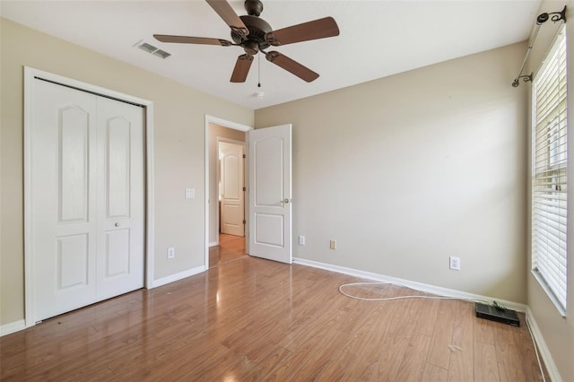 unfurnished bedroom featuring baseboards, wood finished floors, and multiple windows