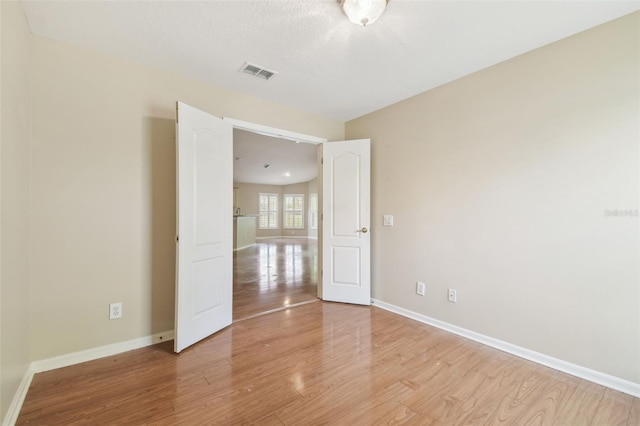 unfurnished room featuring baseboards, visible vents, and light wood finished floors