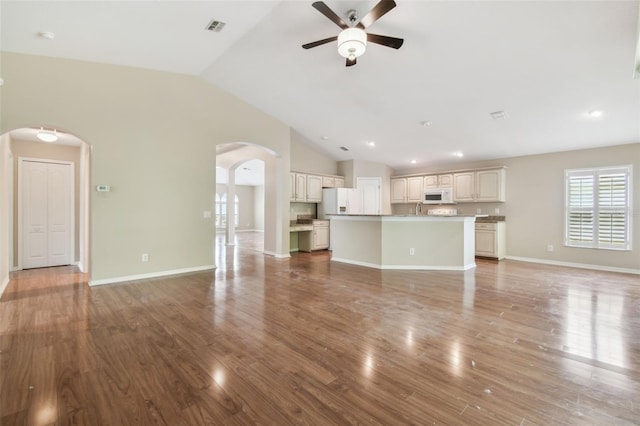 unfurnished living room featuring ceiling fan, arched walkways, wood finished floors, vaulted ceiling, and visible vents