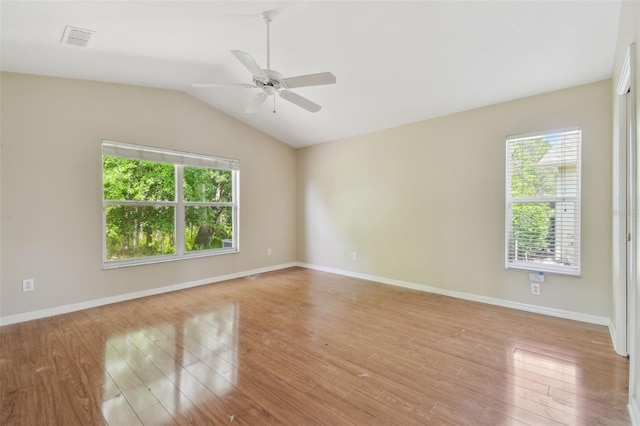 empty room featuring a ceiling fan, visible vents, lofted ceiling, and light wood finished floors