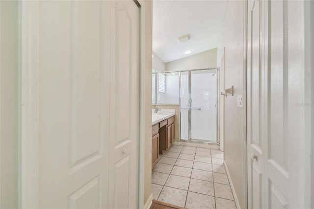 full bathroom with vanity, lofted ceiling, baseboards, tile patterned floors, and a stall shower