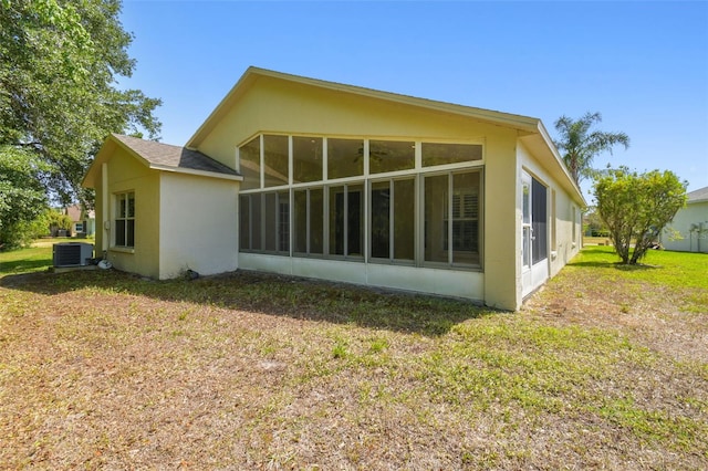rear view of property featuring central air condition unit, a yard, and a sunroom