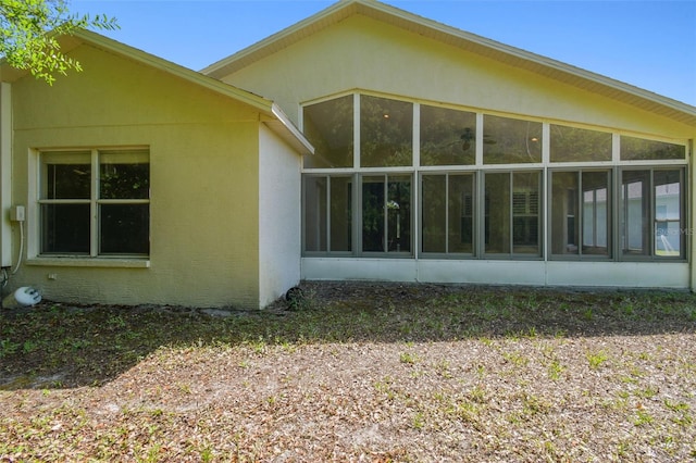 back of house with stucco siding and a sunroom