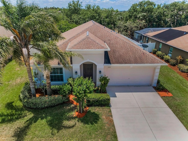 mediterranean / spanish house featuring driveway, roof with shingles, a front lawn, an attached garage, and stucco siding