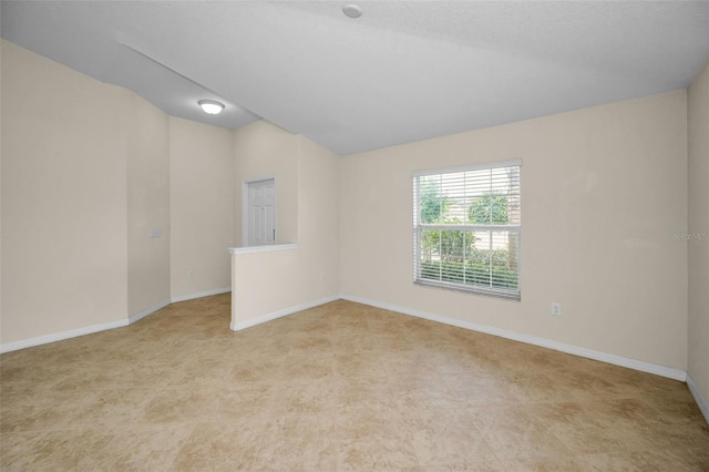spare room with baseboards and vaulted ceiling