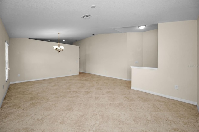 spare room with visible vents, baseboards, vaulted ceiling, and an inviting chandelier