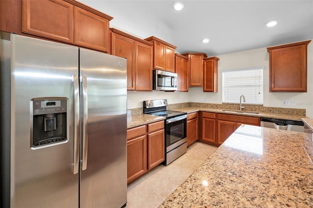 kitchen featuring brown cabinets, stainless steel appliances, recessed lighting, and a sink