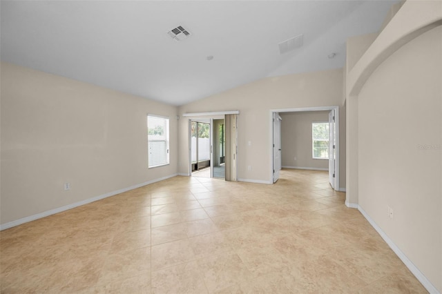 empty room with light tile patterned floors, baseboards, vaulted ceiling, and visible vents