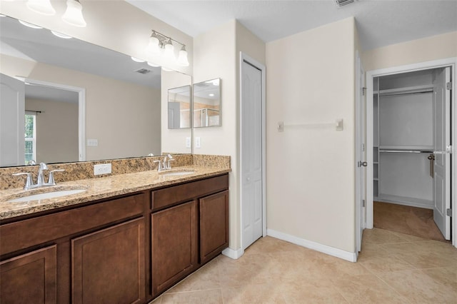 full bathroom with double vanity, tile patterned floors, a spacious closet, and a sink