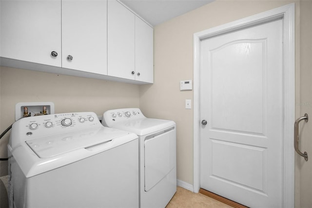 washroom with baseboards, cabinet space, and washer and dryer