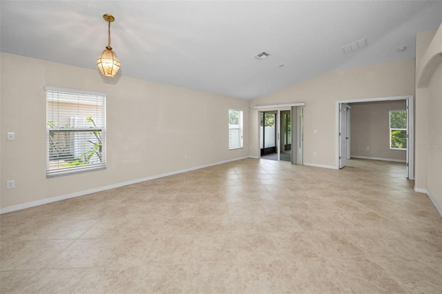 empty room with a healthy amount of sunlight, baseboards, vaulted ceiling, and visible vents