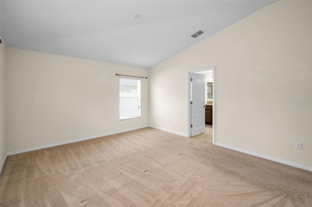 spare room with baseboards, visible vents, light carpet, and lofted ceiling