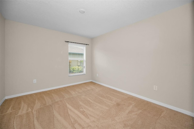 carpeted spare room featuring baseboards