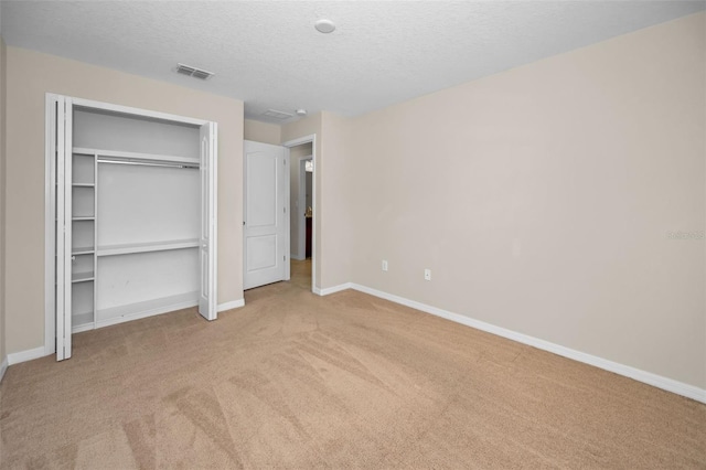 unfurnished bedroom featuring a textured ceiling, carpet, baseboards, visible vents, and a closet
