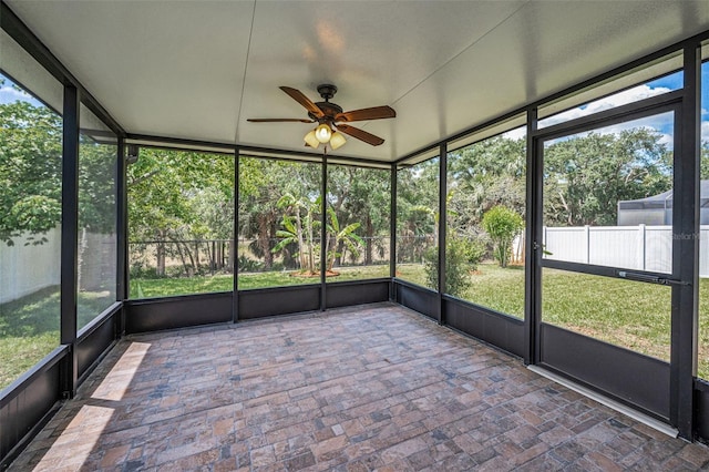 unfurnished sunroom featuring a ceiling fan and a wealth of natural light