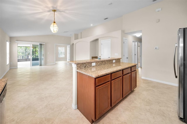kitchen with brown cabinets, light stone counters, freestanding refrigerator, open floor plan, and lofted ceiling