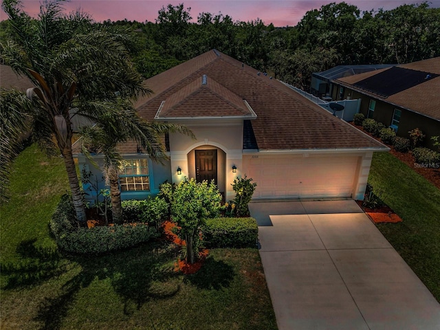10106 Tolman Dr, Hudson, FL 34667 - view of front of home with roof with shingles, an attached garage, concrete driveway, stucco siding, and a front lawn