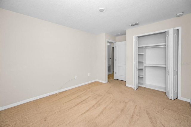 10106 Tolman Dr, Hudson, FL 34667 - unfurnished bedroom featuring light colored carpet, a textured ceiling, baseboards, and a closet