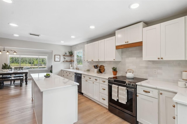 kitchen with electric range, a center island, plenty of natural light, and dishwasher