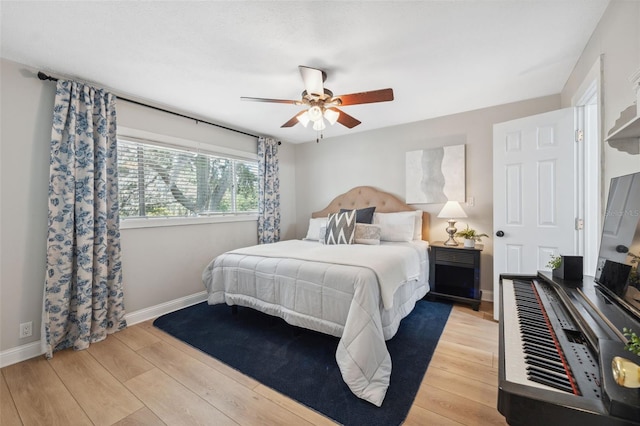 bedroom with light wood-type flooring, a ceiling fan, and baseboards