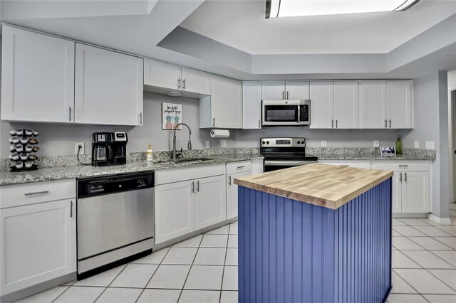 13373 Lawrence St, Spring Hill, FL 34609 - kitchen featuring wooden counters, a sink, white cabinets, stainless steel appliances, and light tile patterned flooring