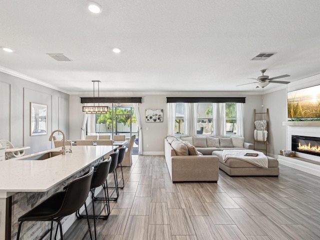 8630 Campus Woods Way, New Port Richey, FL 34655 - living room featuring crown molding, baseboards, visible vents, and a glass covered fireplace