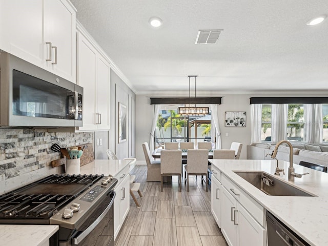 8630 Campus Woods Way, New Port Richey, FL 34655 - kitchen with visible vents, appliances with stainless steel finishes, tasteful backsplash, a sink, and white cabinets
