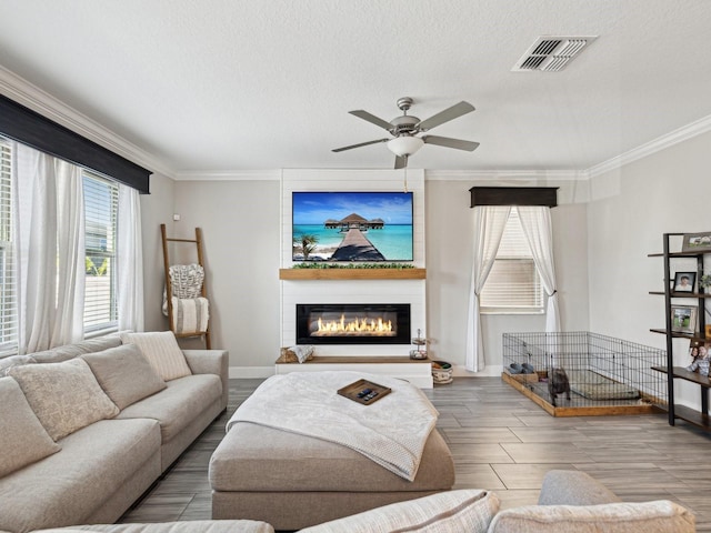 8630 Campus Woods Way, New Port Richey, FL 34655 - living area featuring visible vents, ornamental molding, wood finished floors, ceiling fan, and a large fireplace