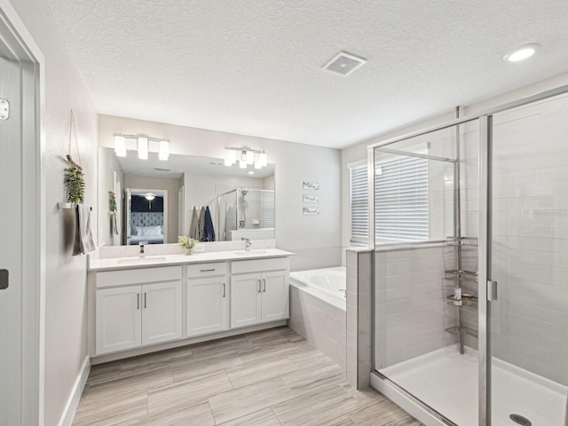 8630 Campus Woods Way, New Port Richey, FL 34655 - bathroom with a sink, double vanity, a textured ceiling, a shower stall, and a garden tub