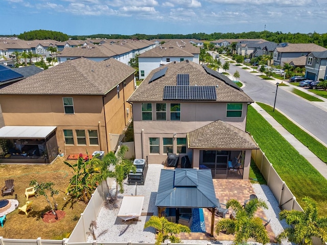 8630 Campus Woods Way, New Port Richey, FL 34655 - rear view of house with a residential view, a sunroom, roof mounted solar panels, a fenced backyard, and stucco siding
