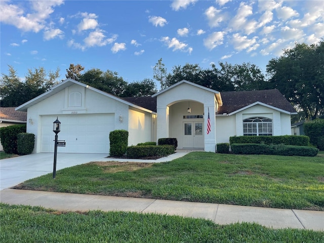 single story home with an attached garage, a front lawn, french doors, and driveway