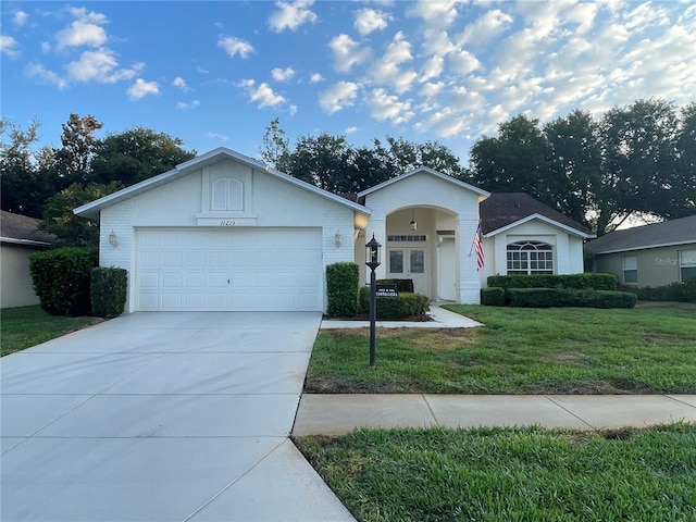ranch-style house featuring concrete driveway, an attached garage, and a front yard