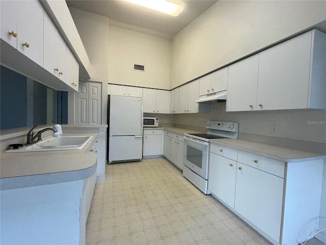 kitchen with a sink, white appliances, light floors, visible vents, and under cabinet range hood