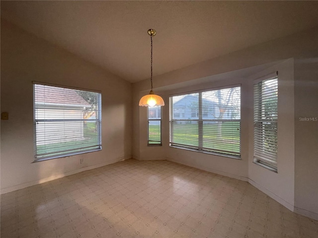 empty room with light floors, vaulted ceiling, and baseboards