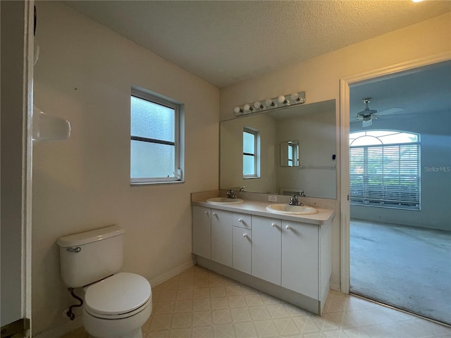 bathroom with double vanity, toilet, a sink, tile patterned floors, and a textured ceiling