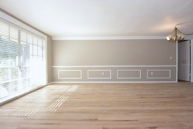 12210 Quail Run Row, Hudson, FL 34667 - spare room featuring an inviting chandelier, ornamental molding, light wood-style flooring, and wainscoting