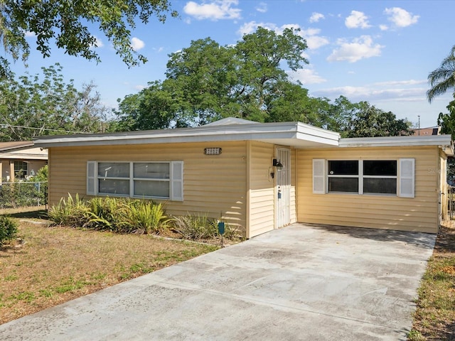 view of front facade with concrete driveway, fence, and a front yard