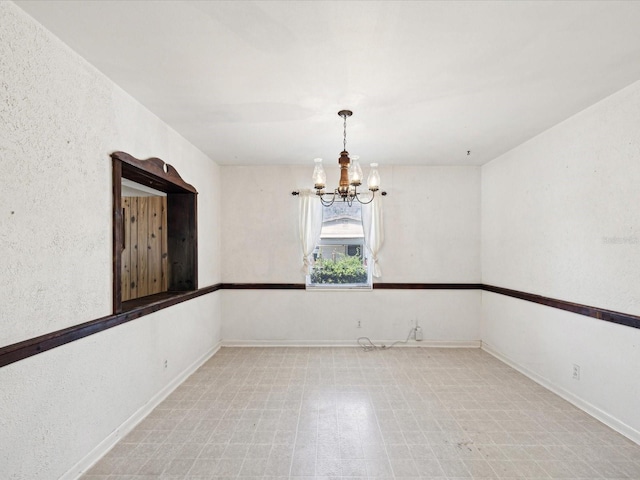spare room with baseboards, a chandelier, and tile patterned floors
