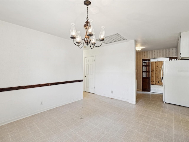 spare room with baseboards, an inviting chandelier, and light floors